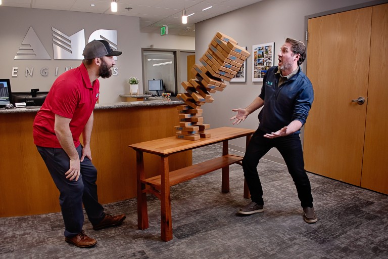 AMC employees looking surprised as a Jenga tower falls over