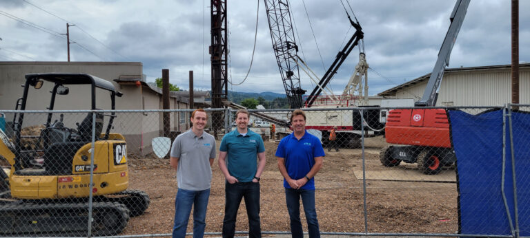Kyle and other AMC employees standing in front of large construction equipment