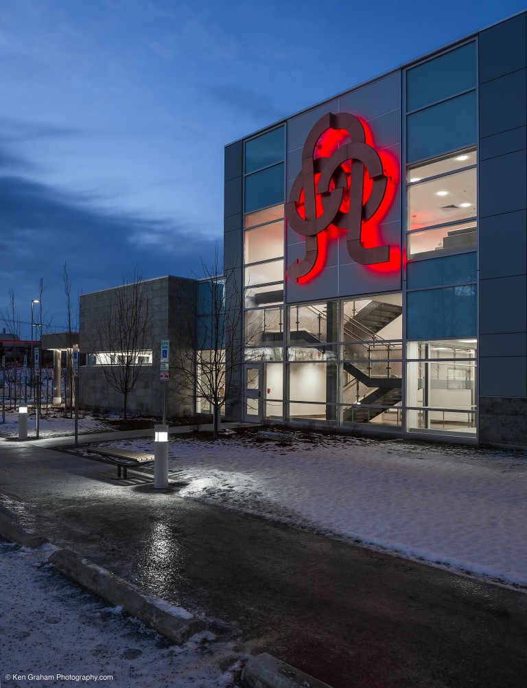 Exterior of brightly lit blood bank of alaska with backlit sculpture on wall