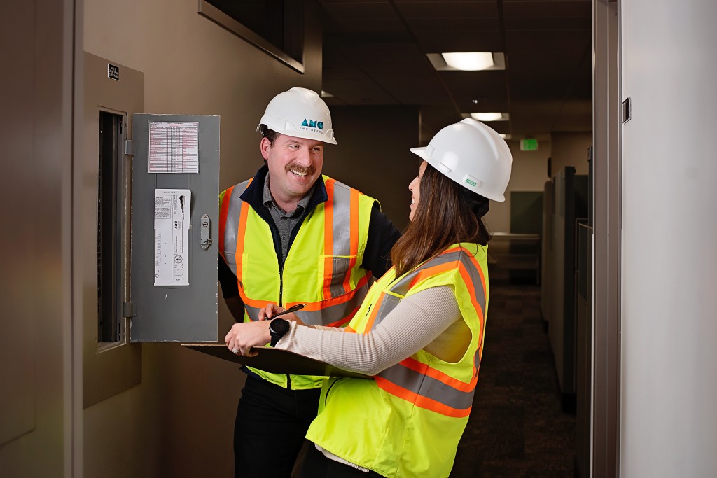 AMC employees in safety gear looking at an electrical panel