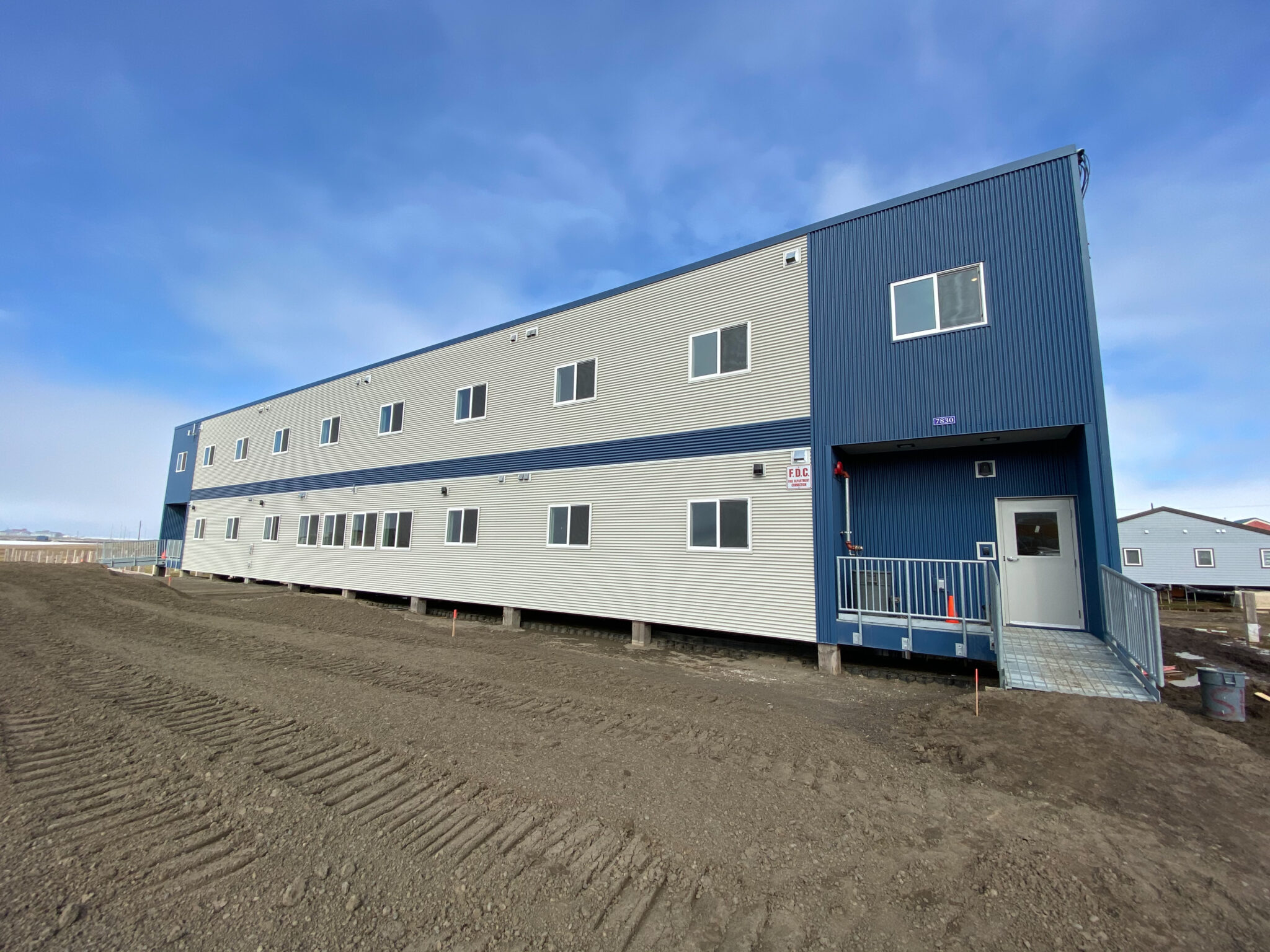 White and blue elevated building with metal grate walls