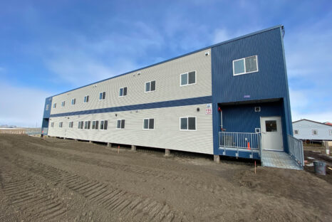 White and blue elevated building with metal grate walls